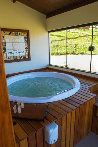 a large jacuzzi tub in a room with windows at Chalé Vale Paraíso in Paraisópolis