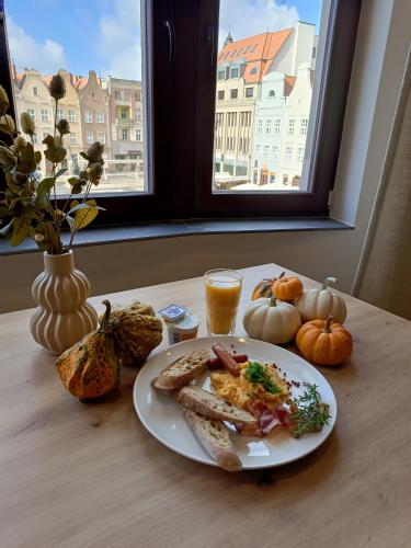a plate of breakfast food on a table with a window at Apartamenty Rynek 13 in Grudziądz