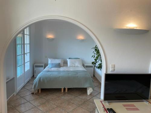 - une chambre avec un lit et une porte voûtée dans l'établissement Domaine des Tuilières avec piscine, à Vallauris