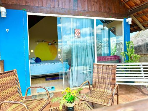 a porch with two chairs and a bed in a room at Chalé Sun Happy in Serra de São Bento
