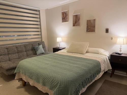 a bedroom with a bed and a couch and a window at Dpto 2 dormitorios cercano Aeropuerto in Concepción