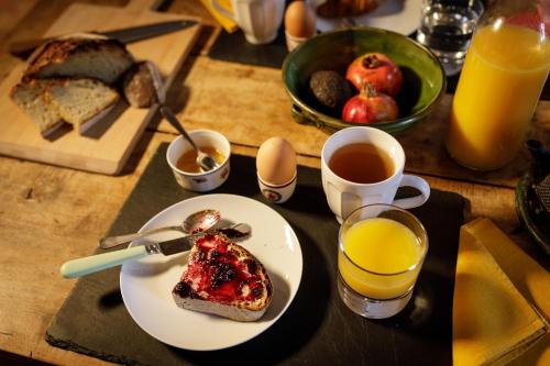 a table with a plate of breakfast food and orange juice at Ostal de la placette in Padern