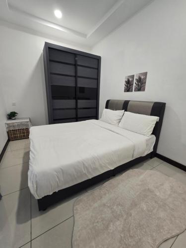 a bedroom with a large bed with white sheets and a rug at Jenz Homestay Bintulu in Bintulu