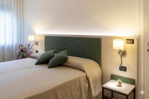 a bedroom with a large bed with two green pillows at Somma Relax Apartment in Sommacampagna