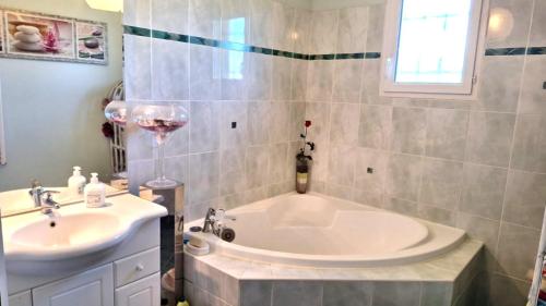 a bathroom with a tub and a sink and a wine glass at Les ptits bonheurs in Frontenac