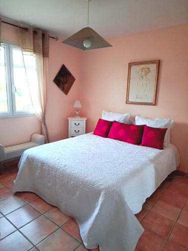 a bedroom with a large white bed with red pillows at Les ptits bonheurs, maison proche de St-Emilion in Frontenac