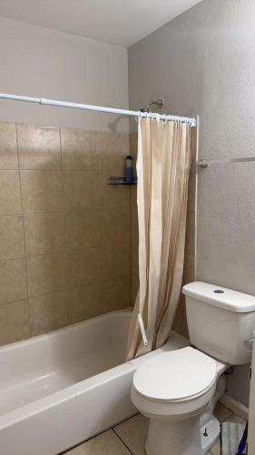 a bathroom with a toilet and a bathtub with a shower curtain at Mike's home 1 in Texas City