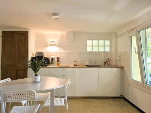 a white kitchen with a table and chairs at T2 proche centre et plages du Pradet in Le Pradet