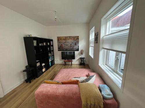 a living room with a pink couch and a window at Cute cottage house in the city centre with terrace in The Hague