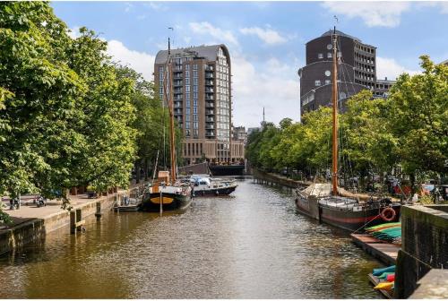 einen Fluss mit Booten in einer Stadt mit hohen Gebäuden in der Unterkunft Cute cottage house in the city centre with terrace in Den Haag