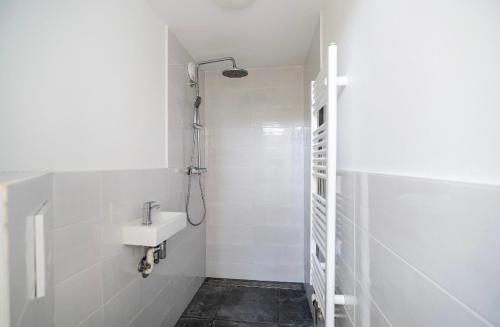 ein weißes Badezimmer mit Waschbecken und Dusche in der Unterkunft Cute cottage house in the city centre with terrace in Den Haag