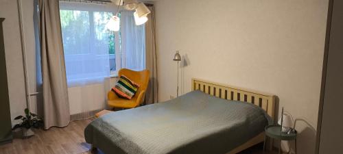 a bedroom with a bed and a chair and a window at Jaukūs, erdvūs, šilti apartamentai in Klaipėda