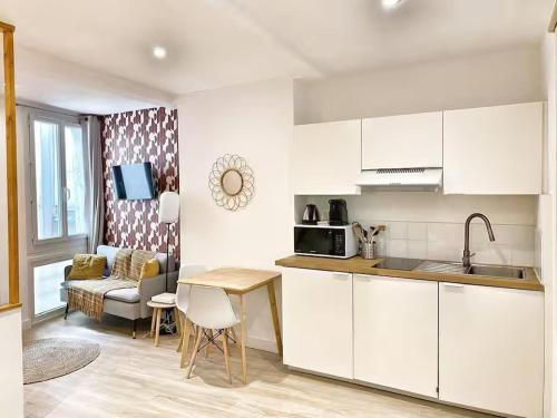 a kitchen with white cabinets and a table and a couch at Le Chabrier By La Familia in Aix-en-Provence