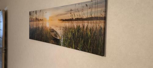 a painting of a lake and a boat on a wall at Jaukūs, erdvūs, šilti apartamentai in Klaipėda
