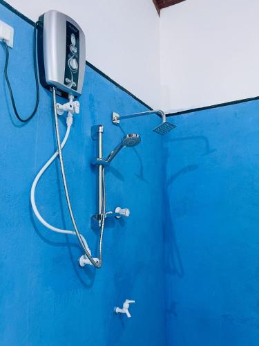 a shower in a blue wall with a blue wall at Sigiri White Queen's Lodge in Sigiriya