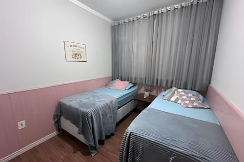 a room with two beds and a window at Quartos Casa do Rosa Casa Compartilada in São João da Boa Vista