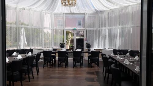 a dining room with tables and chairs and windows at Elfordleigh Hotel in Plymouth