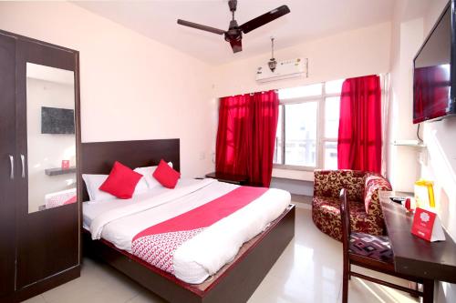 a bedroom with a bed with red curtains and a desk at Hotel O Dwarika Inn in Jabalpur