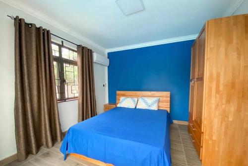 a blue bedroom with a bed and a window at Modern Cosy Villa in Pointe aux Biches