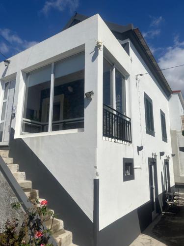 a white house with large windows and stairs at Isabela House in Ponta do Sol