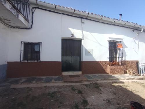 ein weißes Gebäude mit einer Tür und zwei Fenstern in der Unterkunft Casa La Zorrina in Cortelazor