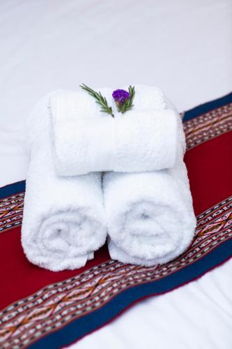 a stack of towels sitting on a bed at Rockrivers Plaza MachuPicchu in Machu Picchu