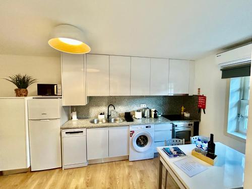 a kitchen with white cabinets and a washer and dryer at Aquae Flaviae Urban Stay - Charm in Chaves