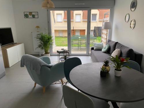 a living room with a couch and a table and chairs at Sous un ciel de somme in Saint-Valery-sur-Somme