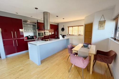 a kitchen with red cabinets and a table and chairs at Salvi's Hideout in Sarisbury Green