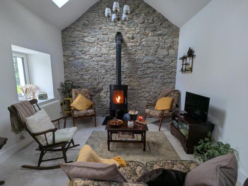 a living room with a stone wall and a fireplace at Joy's River Lodge in Killorglin