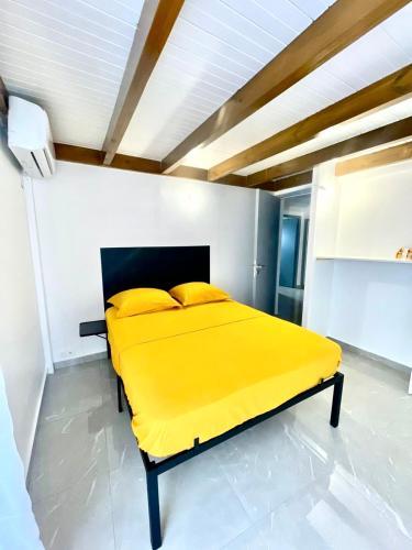 a yellow bed in a room with a ceiling at Nid Créole in Vieux-Habitants