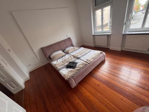 a bed in a room with wooden floors and two windows at Diezer Apartment in Diez