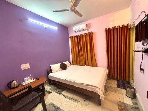 um quarto com uma cama, uma mesa e uma ventoinha de tecto em Hotel Siddhartha em Bodh Gaya