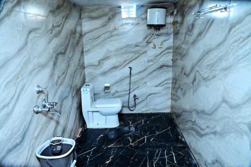 een badkamer met een wit toilet en een marmeren muur bij Jaisalmer adventure Holidays in Jaisalmer