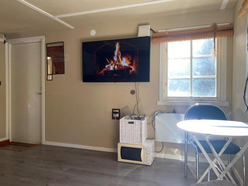 a room with a table and a fire on the wall at Cozy cottage in the woods near lake & sauna in Edsbro