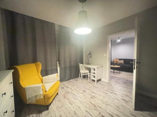 a living room with a yellow couch and a desk at Zlatá Víla by Cañas Apartments V srdci mesta, len pár krokov od hlavného námestia in Rimavská Sobota