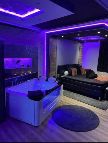 Pause Thermale Suite في هيرستال: غرفة معيشة بها حوض استحمام بإضاءة أرجوانية