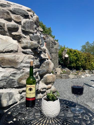 a bottle of wine sitting on a table with a glass at Pink Cottage in Kirkcowan