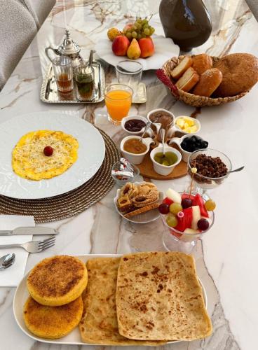 Villa B Marrakech chambres d hôtes Piscine Zéro vis-à-vis في مراكش: طاولة مليئة بأطباق الطعام وأوعية الفاكهة