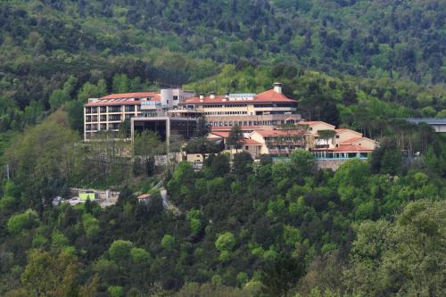 a large building on top of a hill with trees at Mercure Petriolo Siena Terme Spa Hotel in Bagni di Petriolo