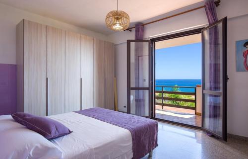 a bedroom with a bed and a view of the ocean at Villa mare panoramica Estia in Brancaleone Marina