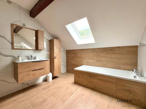 y baño con bañera, lavabo y tragaluz. en Le Cocon de Marnaz - Convivial et Chaleureux, en Marnaz