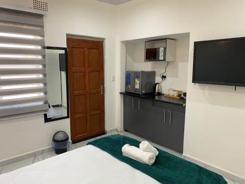 a room with a bed and a flat screen tv at The Palms Guest House in Johannesburg