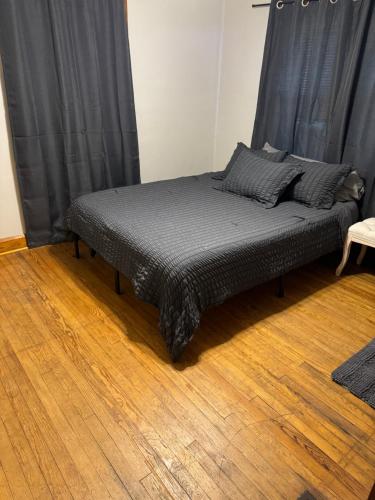 a bed in a room with black curtains and a wooden floor at Private downtown cottage in Indianapolis