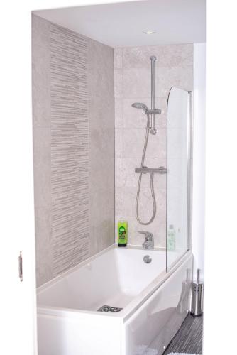 a white bath tub with a shower in a bathroom at Luxury 2-Bed Flat Central Ipswich Parking in Ipswich