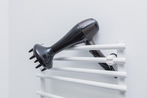 a black hairdryer hanging on a shelf at 1-bedroom loft in Siena Tirgus in Rīga