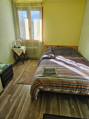 a bedroom with a bed and a table and a window at 1 chambre jaune dans une maison privé in Vernayaz