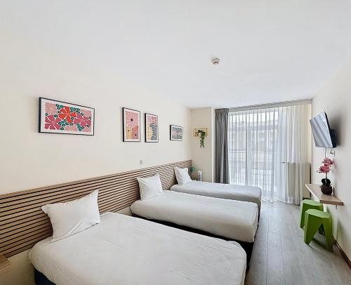 a hotel room with three beds and a window at Slina Hotel Brussels in Brussels