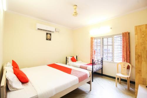 Un dormitorio con una cama, una silla y una ventana en Hotel O Kingston Residency, en Vānivilāsa Puram