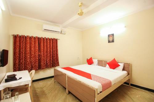 a bedroom with a bed with red pillows and a table at Hotel O Kingston Residency in Vānivilāsa Puram